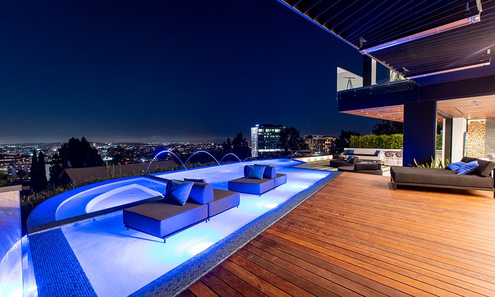 Finished luxury home terrace with pool and city lights at night